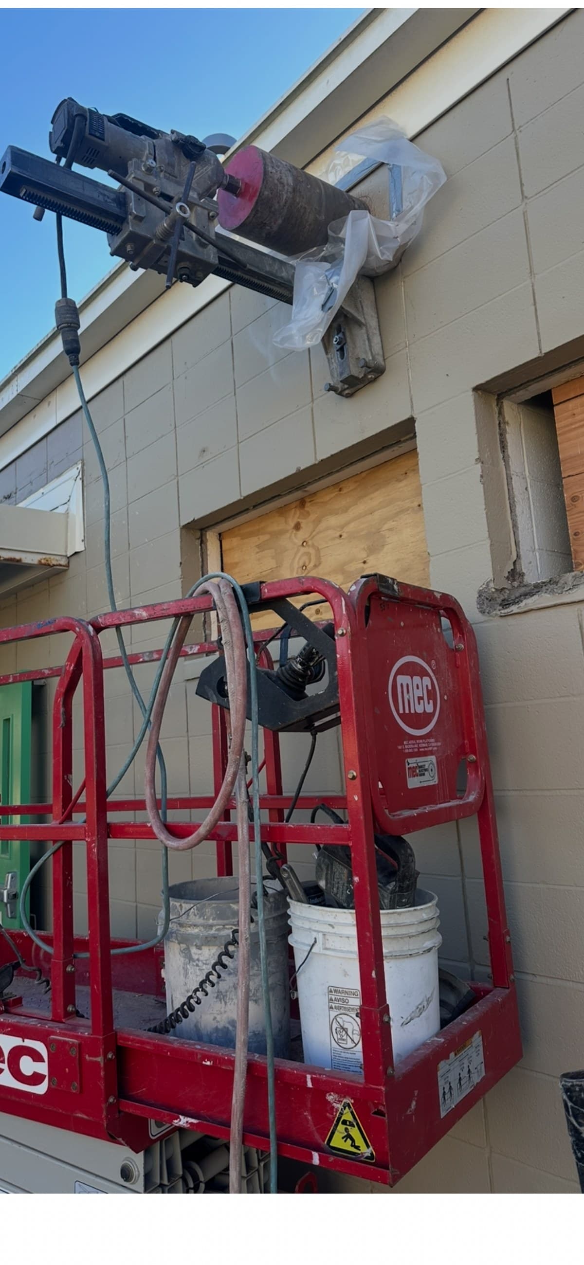 Core drilling from aerial lift — commercial building exterior